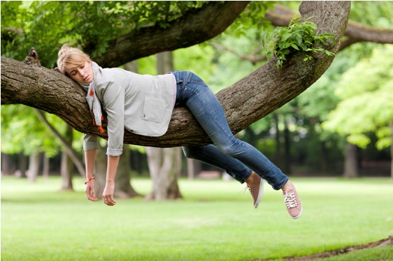Persona cansada sobre un árbol por astenia primaveral