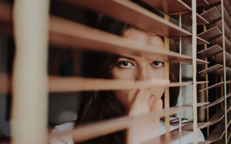 Mujer mirando por la ventana con síntomas de tener problemas de ansiedad