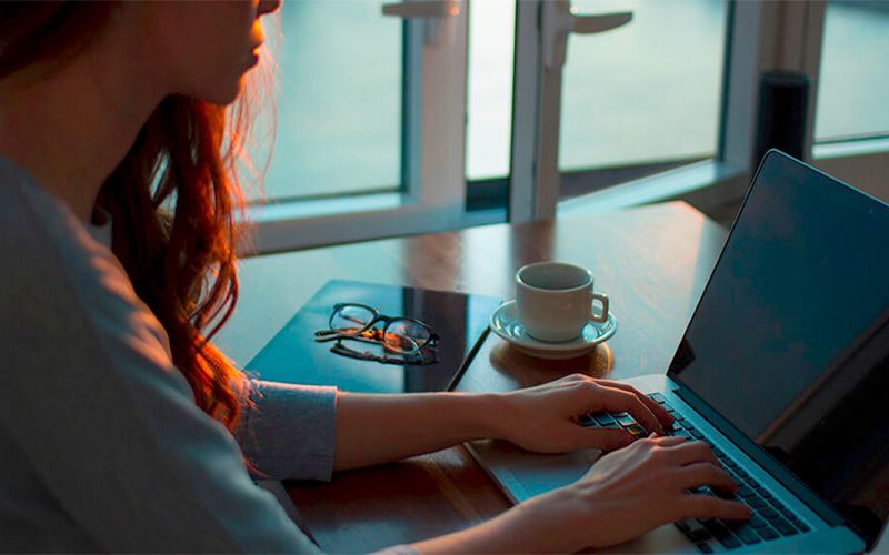 Mujer escribiendo en su ordenador padeciendo síntomas de síndrome de burnout