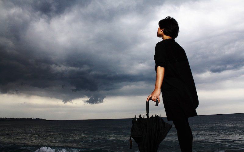 Mujer vestida de negro con el mar de fondo sintiendo angustia y ansiedad