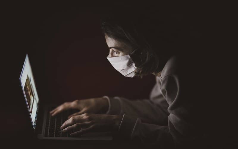 Persona con mascarilla delante de un ordenador buscando información de salud incrementando la relación entre ansiedad y la hipocondría