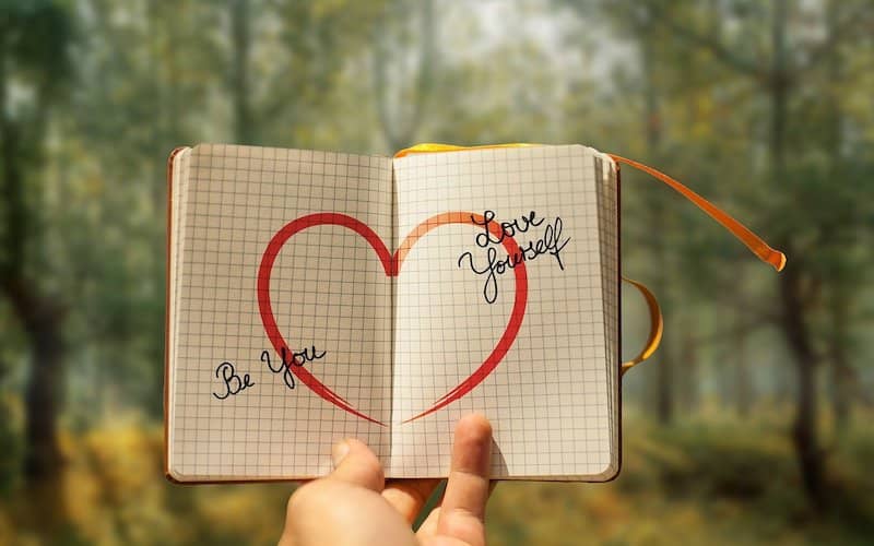 cuaderno con un corazón dibujado y palabras para mejorar la autoestima y salud